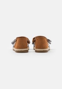 Bruna mocka slip-on skor med ett vävt blått och vitt randigt mönster och en naturlig jutesula. Har en rundad tå och mjuk textur.