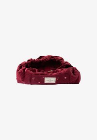 Cama para mascotas acolchada en color burdeos con una textura suave y bordado floral, que cuenta con un borde acolchado y una etiqueta de marca en el costado.