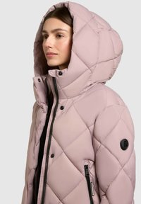 Polstret hættejakke i blød pink med diamantquiltmønster, der har sort lynlås, trykknapper og logo-patch på ærmet.