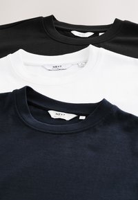 Drei gefaltete T-Shirts mit Rundhalsausschnitt in Schwarz, Weiß und Dunkelmarine, jeweils mit sichtbarem NEXT-Etikett und lässiger Passform.