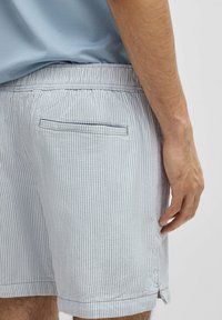 Gestreepte blauwe en witte shorts met een elastische tailleband, achterzak en een omgeslagen zoom, gemaakt van lichte stof.