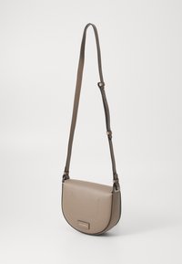 Béžová kožená crossbody taška s zakřiveným tvarem, nastavitelným popruhem a jemným prošíváním na přední straně. Obsahuje kovov�é detaily.