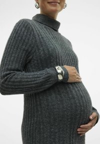 Maglione grigio a coste con collo alto, indossato sopra un pancione. Presenta maniche lunghe e un braccialetto d'argento su un polso.