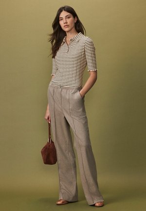 Triibuline polo-särk kreemi ja tumeda pruuni värviga; lühikesed varrukad kaarjate äärtega. Beež, tekstureeritud laiade jalgadega püksid. Pruun käekott.