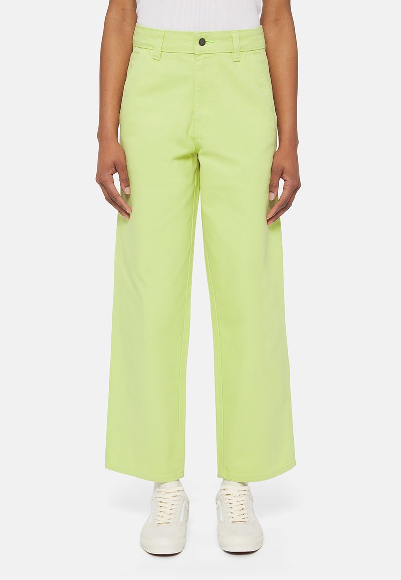 Vihreät leveät housut, jotka on valmistettu puuvillatwillistä, jossa on nappikiinnitys ja vyölenkit. Yhdistetty valkoisiin tennareihin.