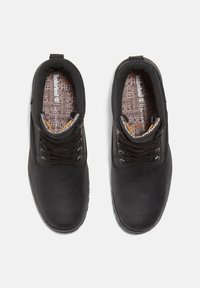 Zwarte leren schoenen met een gladde textuur, ronde neus en vetersluiting. Inclusief een gevoerde zool met lichtbruine accenten.