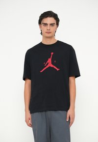 Mustmust värvi puuvillane t-särk, mille keskel on suur punane "Jumpman" logo, lühikesed varrukad ja ümar kaelus, lõdva lõikega.
