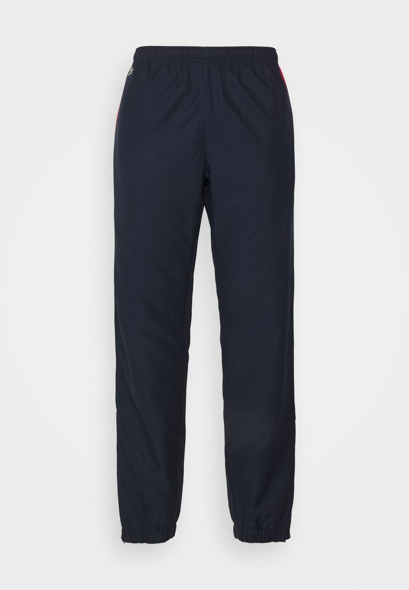 Pantalons de jogging bleu marine avec une taille élastique et des poignets, présentant des accents latéraux d'une couleur contrastante. Tissu léger et texture lisse.