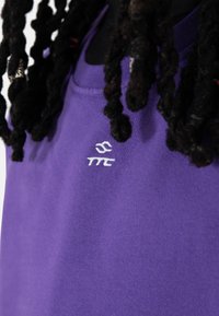 Lilla bomullsskjorte med rund hals og brodert hvitt logo på venstre bryst. Myk tekstur med minimale designdetaljer.