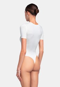 Witte body met korte mouwen, een aansluitend ontwerp, hoge beenopeningen en een gladde textuur, die een minimalist aesthetic toont.