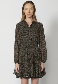 Abito floreale nero realizzato in tessuto leggero, con colletto, maniche lunghe e una gonna svasata con orlo arricciato.