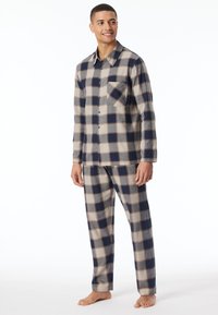 Set di pigiama in flanella a quadri nei colori blu navy, beige e grigio. La camicia presenta bottoni e una tasca sul petto, mentre i pantaloni hanno una vita elasticizzata.