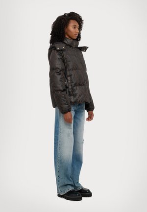 Doudoune noire avec un motif texturé, col montant et poches zippées, associée à un jean large délavé bleu clair et des chaussures à plateforme noires.