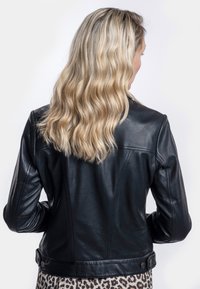 Schwarze Lederjacke mit taillierter Passform, sichtbaren Nähten und Knopfdetails an der Taille, von hinten betrachtet mit welligem Haar.