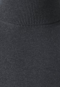 Pull à col roulé gris foncé avec un col côtelé et une texture lisse. Le tissu semble léger et légèrement extensible.