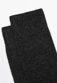 Calze di lana nera con un bordo a costine. La texture è morbida e calda, con una finitura liscia e un design semplice e classico.