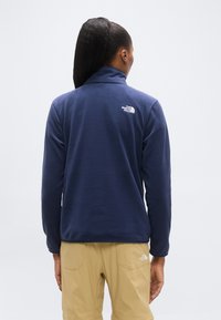 Μπλε σκοτεινή ζακέτα από φλις με ψηλό γιακά. Διαθέτει μικρό λευκό λογότυπο στην πλάτη. Φορεμένη με ανοιχ τόχρωμο παντελόνι. Μαλακή υφή, άνετη εφαρμογή.