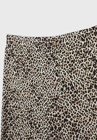 Tissu à imprimé léopard avec des taches noires et brunes denses et irrégulières sur un fond beige, avec une ceinture et des coutures visibles.