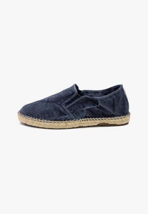 Marineblauwe espadrilles zonder hak, gemaakt van zacht materiaal, met een geweven jute zool en elastische zijaccenten voor gemakkelijk aan- en uittrekken.