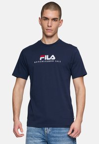 Camiseta de algodón azul marino con mangas cortas, con el logo de Fila en bordado rojo y blanco. Cuello redondo y corte relajado.