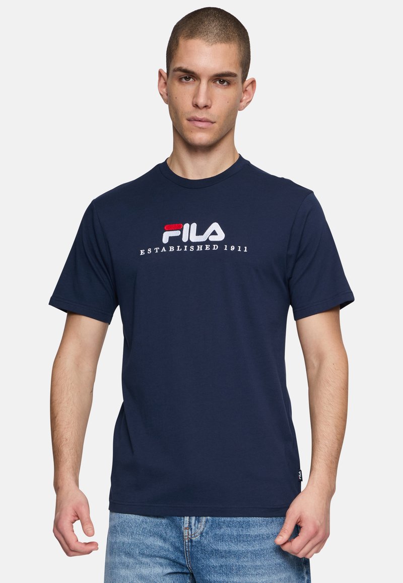 Camiseta de algodón azul marino con mangas cortas, con el logo de Fila en bordado rojo y blanco. Cuello redondo y corte relajado.