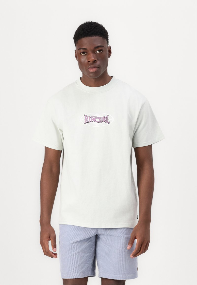 Camiseta de algodón verde claro con cuello redondo y mangas cortas, que presenta un logo gráfico rosa en la parte delantera. Combinada con pantalones cortos a rayas azules.