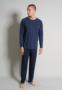 Langärmeliges Pyjama-Set in Marineblau aus weichem Stoff mit Raglanärmeln. Es bietet eine entspannte Passform und passende Hosen, ideal für Nachtwäsche.