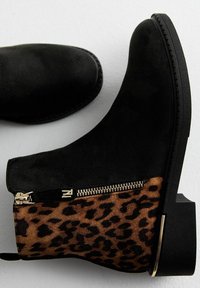 Černé kotníkové boty s panely s leopardím vzorem, boční zip a nízké blokové podpatky s kovovými detaily.