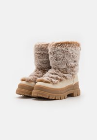 Kratkie zābaki ar mākslīgo kažokādu iekšpusē, khaki krāsā, ar masīvu gumijas zoli ar saķeres detaļām un teksturētām brūnām akcentiem augšpusē.