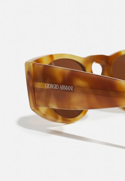 Tortijas sauļošanās brilles ar izteiksmīgu formu, ar brūnām tonētām lēcām. "Giorgio Armani" ir izdrukāts sānos sudraba burtiem.