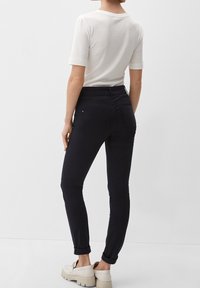 Donkerblauwe jeans met een slim fit, voorzien van opgerolde manchetten en achterzakken. Gecombineerd met een wit T-shirt met korte mouwen van zachte stof.