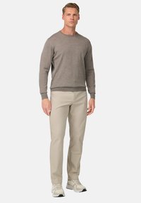 Lys grå sweater, rund halsudskæring, ribbede manchetter og kant, parret med beige bukser, lige ben, glat stof, båret med lyse sneakers.