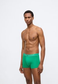 Zöld pamut boxeralsó fehér logós derékrészel. Testhez simuló dizájn, sima textúra és középmagas hossza.