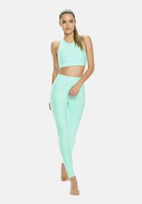 Mentolová zelená crop top a legíny z hladkej, elastickej látky. Priliehavý dizajn s vysokým pásom, vhodný na atletické aktivity.