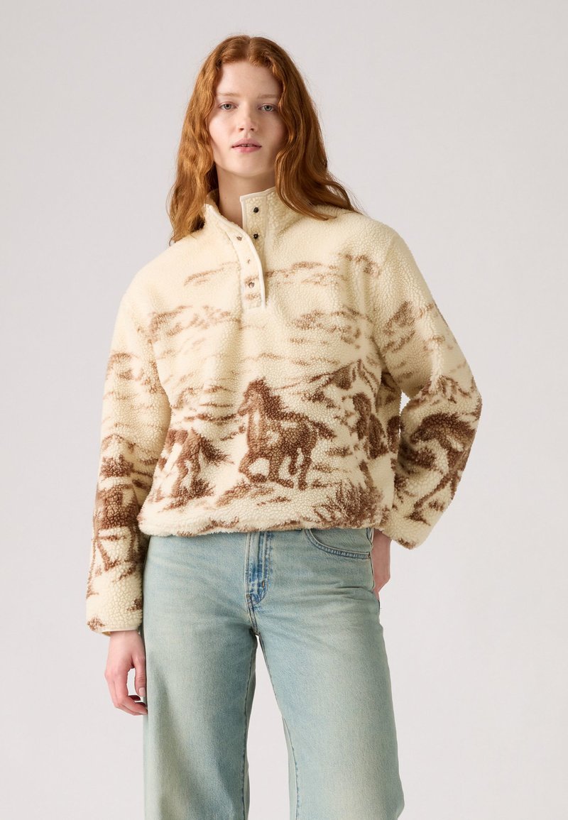 Fleece-Pullover in Creme mit braunem Pferdeprint, mit einem hohen Kragen und einer Knopfleiste mit vier Knöpfen sowie langen, weiten Ärmeln.