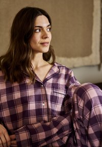 Purple and pink checkered pajama set with a button-down shirt and loose-fitting pants; soft fabric with contrasting dark accents.