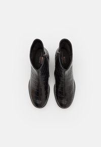 Bottines en cuir noir avec un motif crocodile, bout rond et zips latéraux. Texture lisse et silhouette élégante.