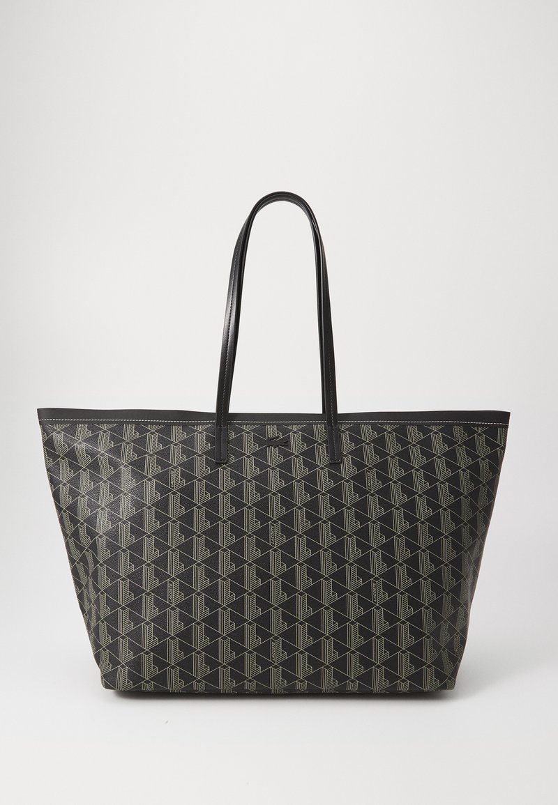 Romslig svart totebag med et geometrisk mønster i beige. Har robuste sorte lærhender og en flat form. Teksturert syntetisk materiale.