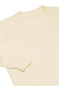 V-hals strikket sweater i blød kremfarve, med ribkant ved ærmer og kant, glat tekstur og en tætsiddende Silhuet.