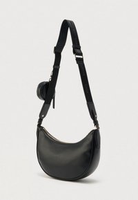 Fekete, sarló alakú bőr válltáska állítható, márkás pánttal, a pánt csatja közelében kis, kerek zsebbel.