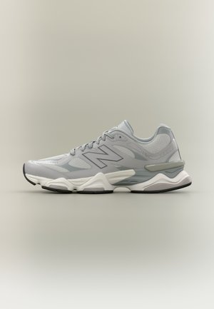 Scarpa atletica grigio chiaro con tomaia in mesh, dettagli tono su tono e suola ammortizzata. Caratterizzata da una midsole bianca e una suola esterna in gomma nera.