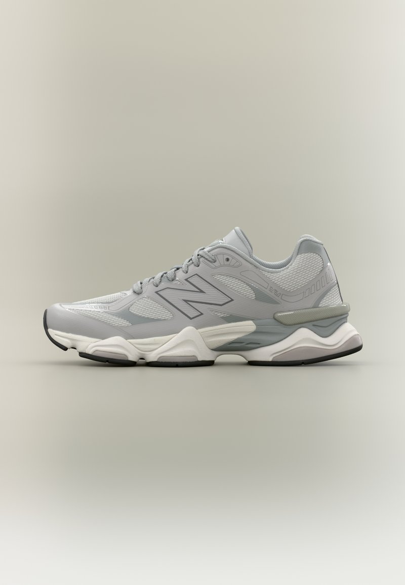 Chaussure de sport gris clair avec tige en mesh, accents ton sur ton et semelle coussinée. Comprend une semelle intermédiaire blanche et une semelle extérieure en caoutchouc noire.