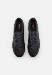 Black athletic shoes with red accents, featuring a smooth, synthetic upper, rounded toe, and flat laces. Designed for comfort and performance.