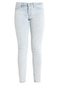 Jeans skinny azul claro de denim, con cintura alta, diseño de cinco bolsillos y cierre de botón. Textura suave con un ligero desgastado.