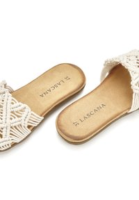 Sandali macramè bianchi con suola piatta, caratterizzati da un design a trama texture e una soletta in ecopelle marrone. Nome del marchio "LASCANA" visibile.