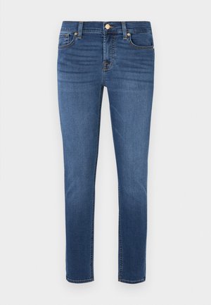Jean skinny en denim bleu foncé avec une texture lisse, présentant une fermeture à glissière et un bouton, cinq poches et des surpiqûres contrastées.