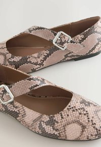 Pink and brown snake-print flats with a cross strap design and silver buckle accents. Smooth texture and flat sole.