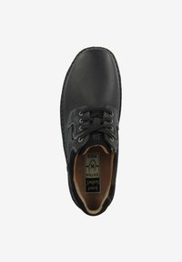 Scarpa in pelle nera con superficie texturizzata, punta tonda e design con lacci. Presenta un interno beige e una soletta con marchio. Etichetta della taglia visibile.
