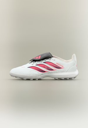 Λευκό ποδοσφαιρικό παπούτσι Adidas Predator με ροζ ρίγες και μαύρο κάλυμμα κορδονιών, εμφανίζεται από το πλάι σε ουδέτερο φόντο.