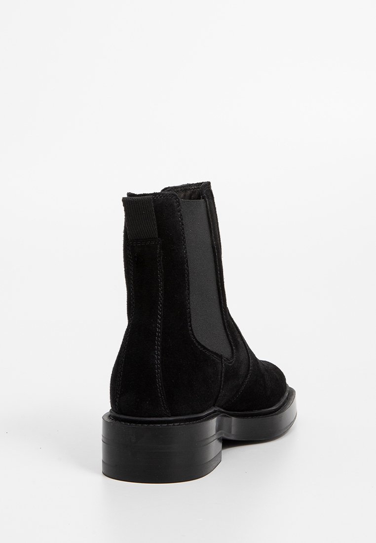 Stivaletti in suede neri alla caviglia con pannelli laterali elasticizzati, punta arrotondata e suola in gomma spessa. Presentano cuciture pulite e una texture morbida.